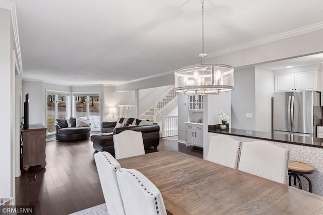 dining room with dark wood-style floors, stairs, crown molding, and an inviting chandelier