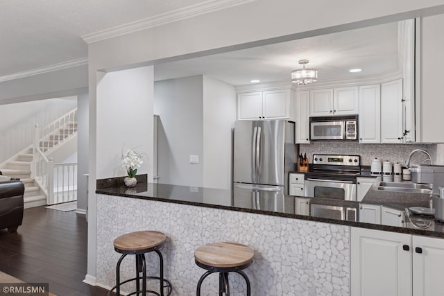 kitchen with stainless steel appliances, ornamental molding, a sink, and white cabinetry