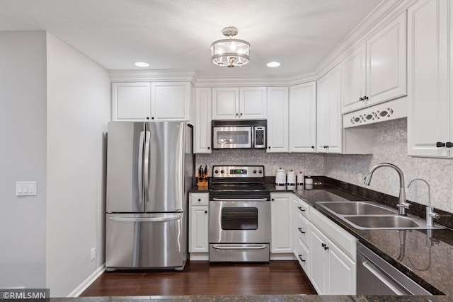 kitchen with dark wood-style floors, appliances with stainless steel finishes, white cabinets, and a sink