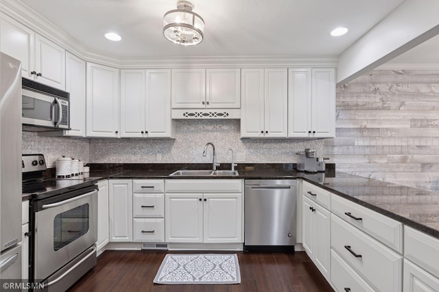 kitchen featuring decorative backsplash, dark wood finished floors, appliances with stainless steel finishes, white cabinetry, and a sink