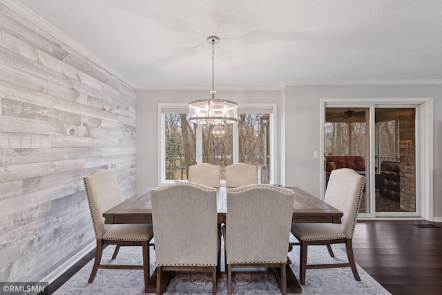 dining area featuring crown molding, a textured ceiling, wood finished floors, and an inviting chandelier