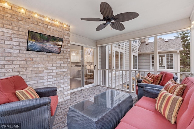 living area with a wealth of natural light, ceiling fan, and brick wall