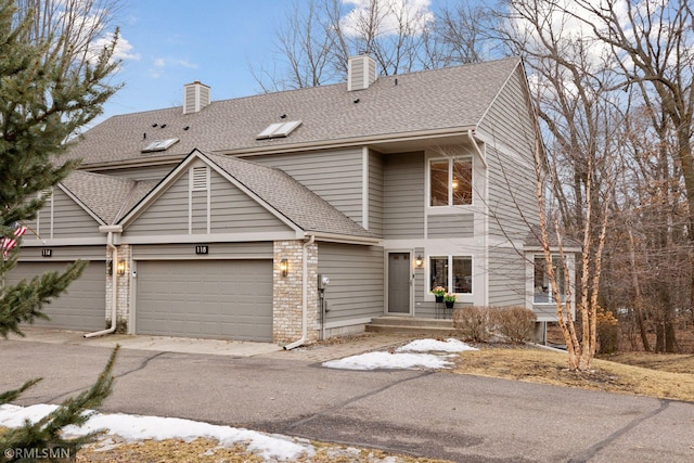 view of front of home featuring brick siding, an attached garage, a chimney, and roof with shingles