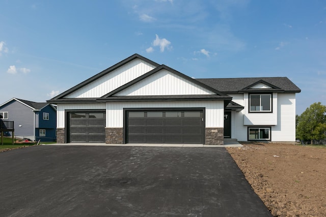 view of front facade featuring a garage, stone siding, and aphalt driveway