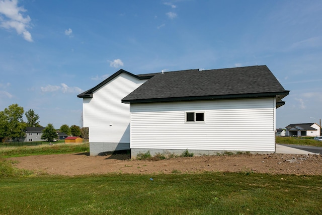 view of home's exterior with a shingled roof and a yard