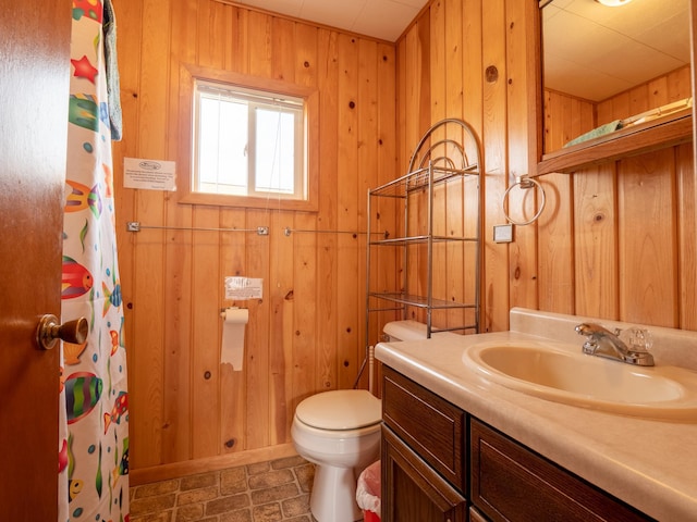 bathroom with a shower with shower curtain, toilet, wood walls, vanity, and baseboards