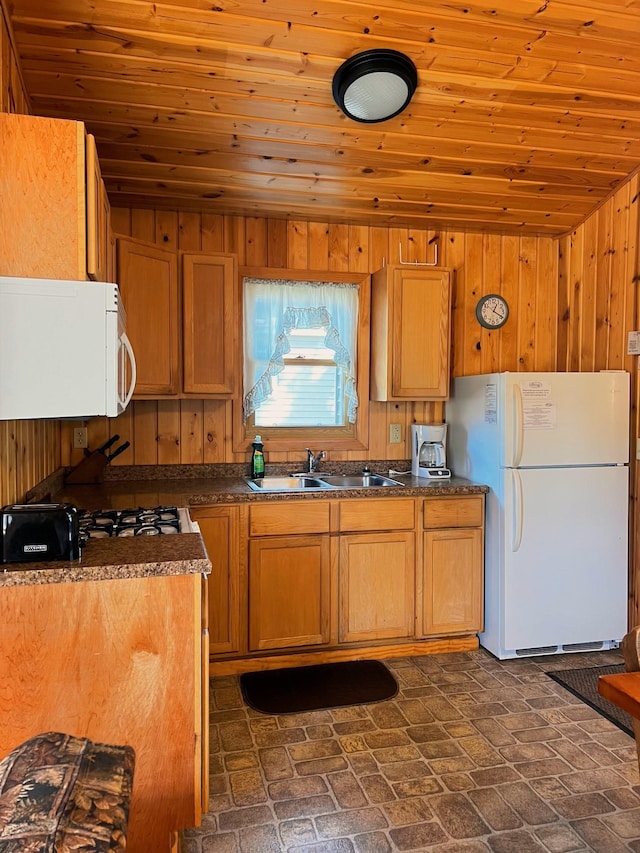 kitchen with dark countertops, white appliances, wood ceiling, and a sink