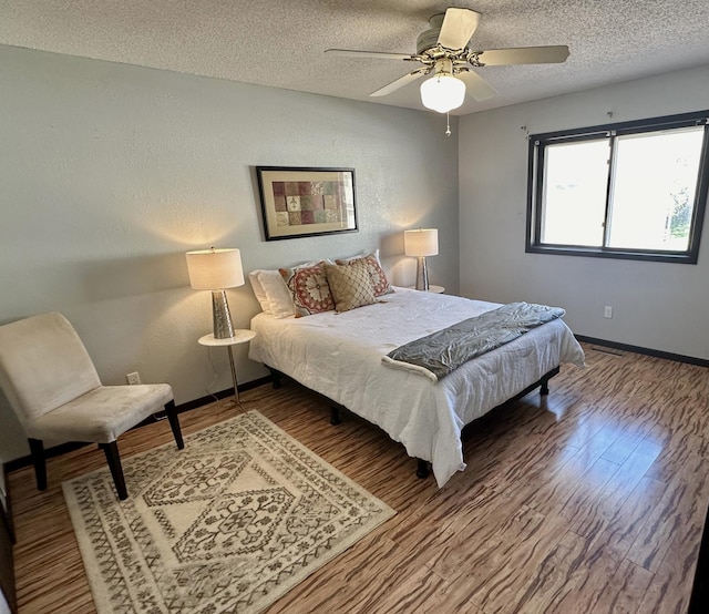 bedroom featuring a textured ceiling, wood finished floors, and baseboards