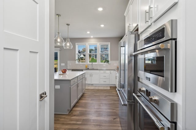 kitchen with decorative backsplash, dark wood finished floors, freestanding refrigerator, light countertops, and recessed lighting