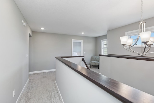 hallway featuring recessed lighting, light colored carpet, an upstairs landing, baseboards, and an inviting chandelier