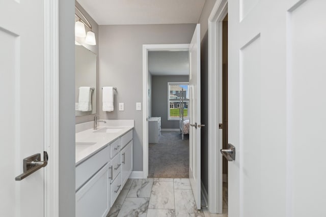 full bath featuring marble finish floor, a sink, baseboards, and double vanity