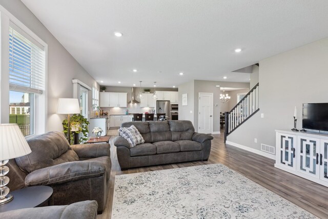 living room featuring visible vents, dark wood-style floors, stairway, a notable chandelier, and recessed lighting