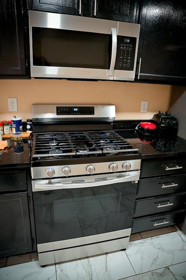 kitchen with stainless steel appliances, marble finish floor, and dark cabinets