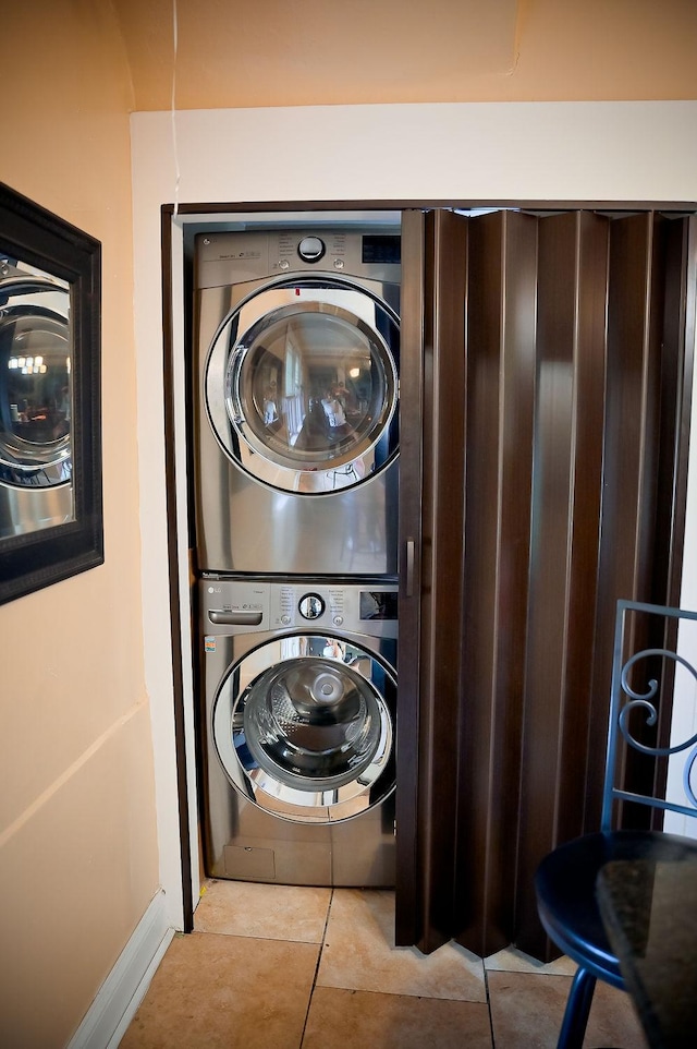 clothes washing area featuring stacked washer / dryer, laundry area, and light tile patterned floors