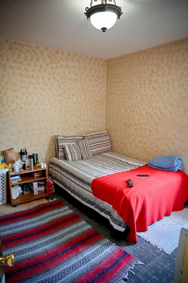 bedroom featuring a textured ceiling and wallpapered walls