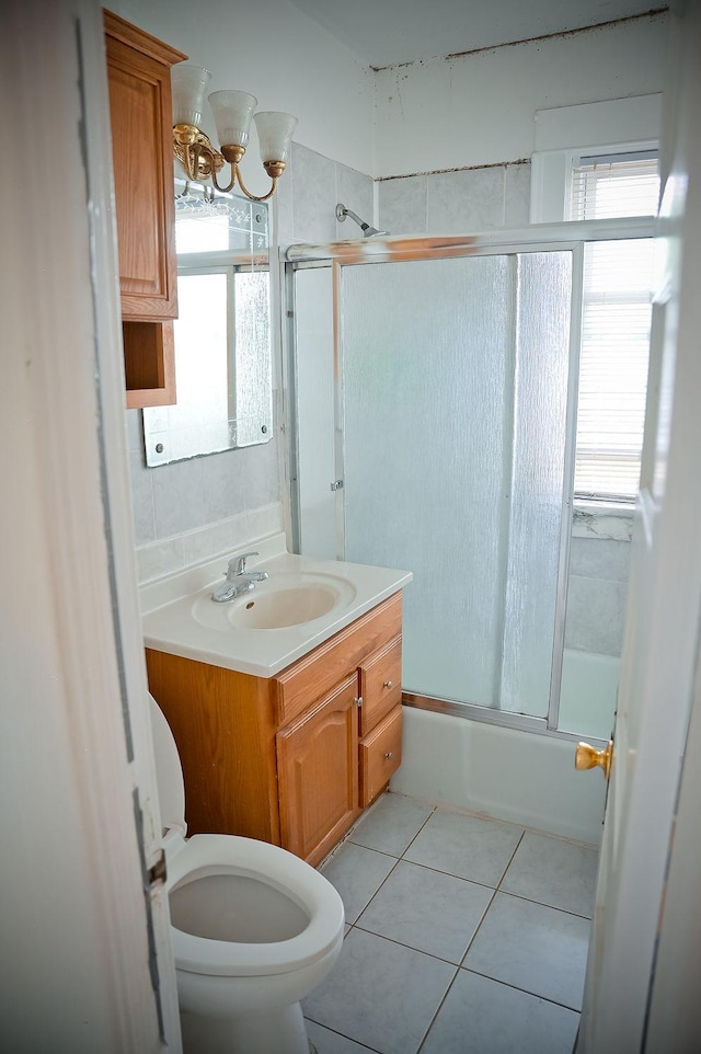 bathroom with toilet, tile patterned flooring, combined bath / shower with glass door, and vanity