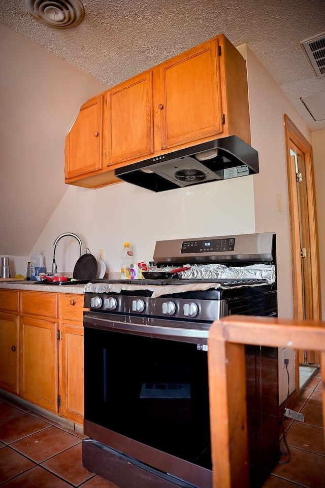 kitchen with range hood, visible vents, gas stove, a textured ceiling, and tile patterned flooring