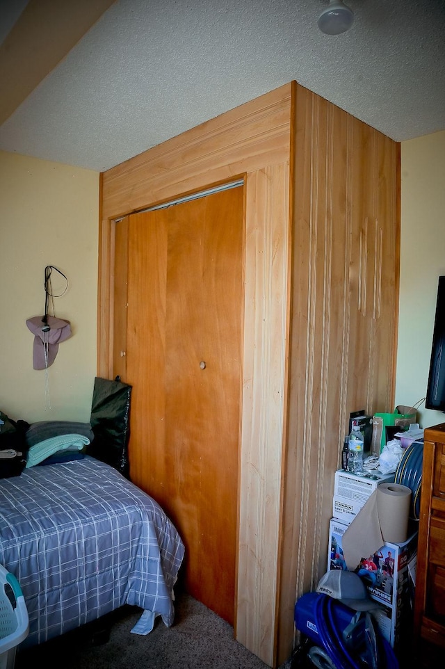 carpeted bedroom featuring a textured ceiling and wooden walls