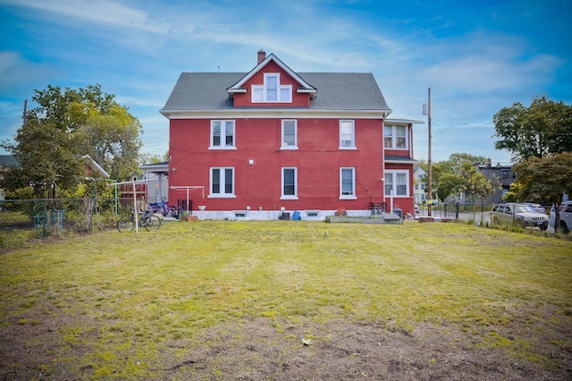 back of property featuring brick siding, a fenced backyard, a chimney, and a yard