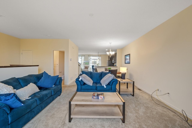 living area featuring light carpet, baseboards, and a chandelier