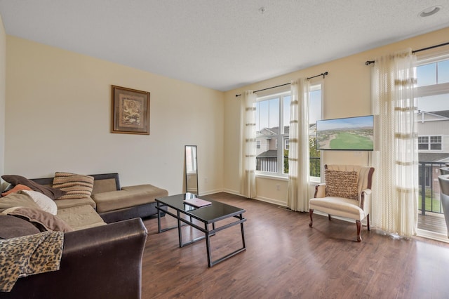 living area with a healthy amount of sunlight, dark wood finished floors, and a textured ceiling