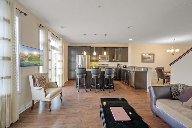 living room featuring an inviting chandelier, baseboards, dark wood-type flooring, and recessed lighting