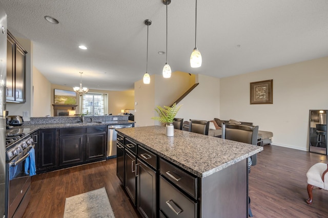 kitchen featuring appliances with stainless steel finishes, a sink, dark wood finished floors, and a kitchen breakfast bar