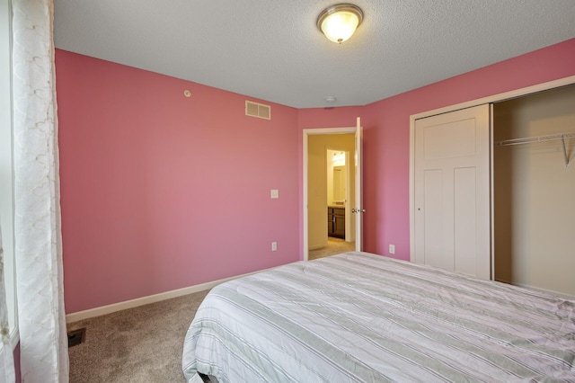 carpeted bedroom with a textured ceiling, a closet, visible vents, and baseboards