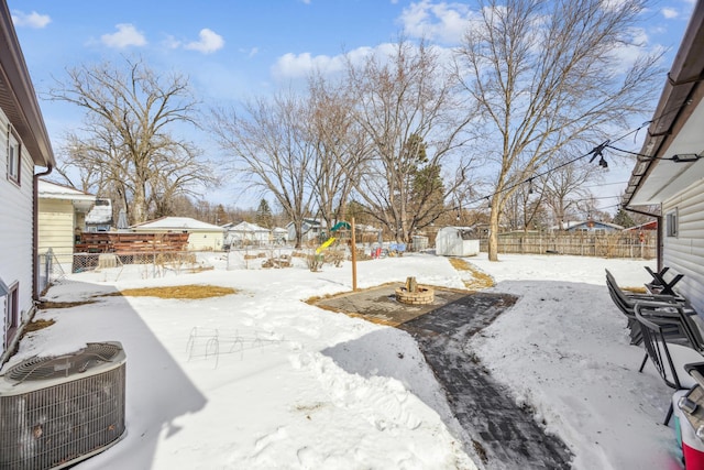 yard covered in snow with central AC, a patio, and a fenced backyard