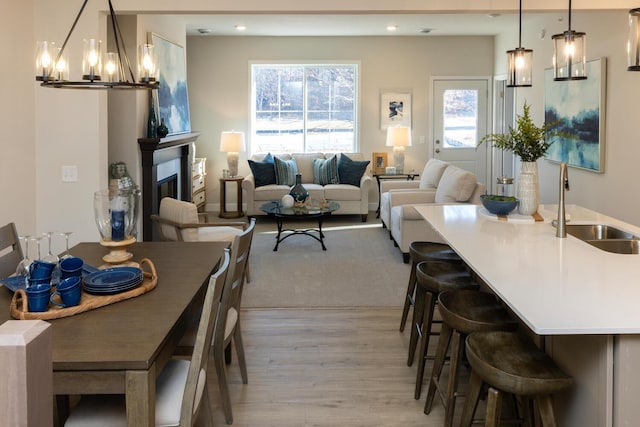 dining space with a glass covered fireplace, recessed lighting, light wood finished floors, and an inviting chandelier