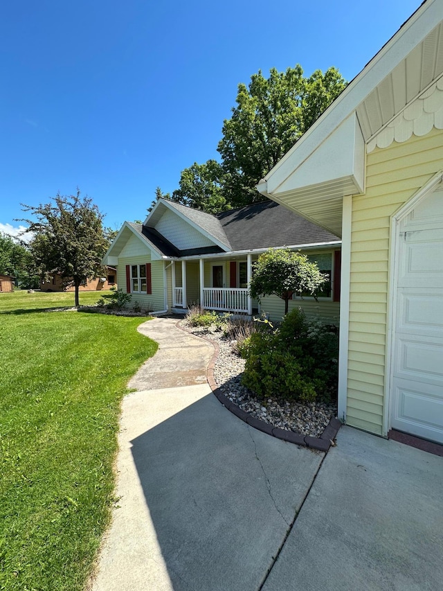 view of front of home with covered porch, a front yard, and a garage