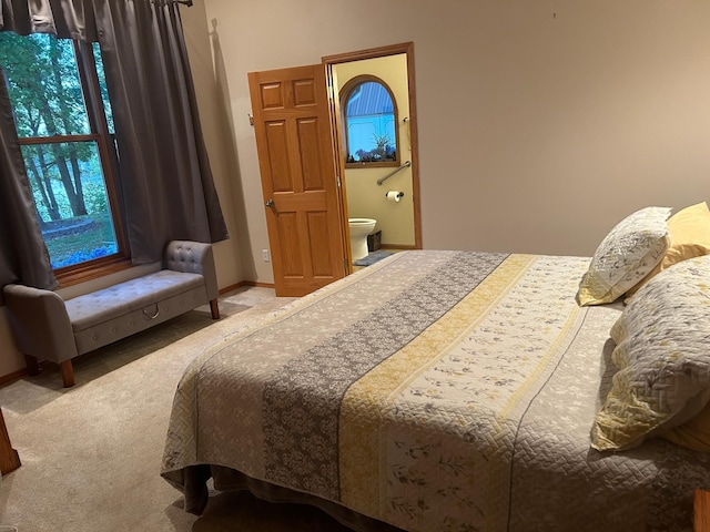 carpeted bedroom featuring connected bathroom and baseboards