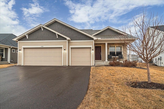 craftsman house with aphalt driveway, covered porch, and a garage