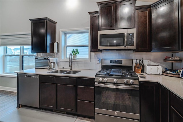 kitchen featuring stainless steel appliances, light countertops, backsplash, a sink, and dark brown cabinetry