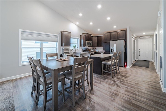 dining room with high vaulted ceiling, baseboards, wood finished floors, and recessed lighting