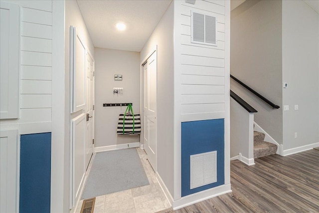 hallway featuring baseboards, stairs, and visible vents