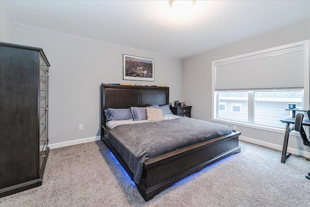 bedroom featuring light carpet, a textured ceiling, and baseboards