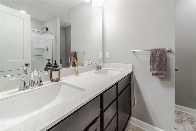 full bathroom with a sink, a shower stall, baseboards, and double vanity