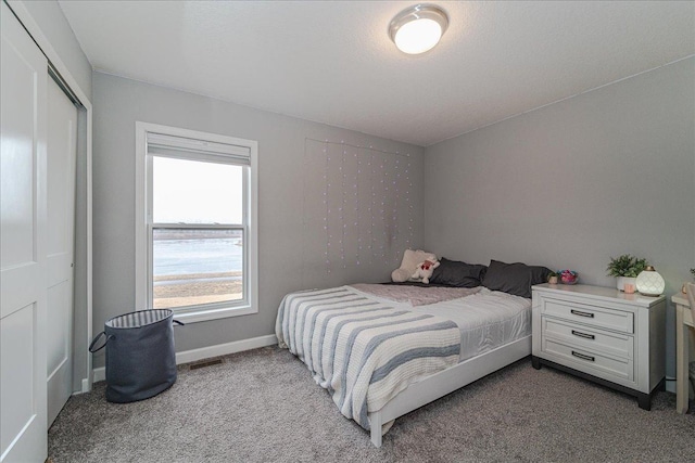 bedroom featuring visible vents, a closet, baseboards, and carpet flooring