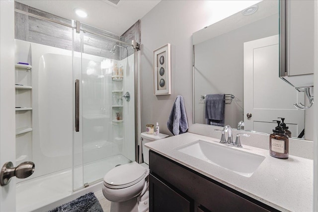 bathroom with a stall shower, vanity, and toilet