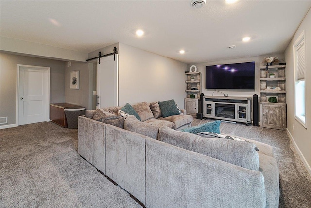 living area featuring carpet floors, recessed lighting, a barn door, a glass covered fireplace, and baseboards