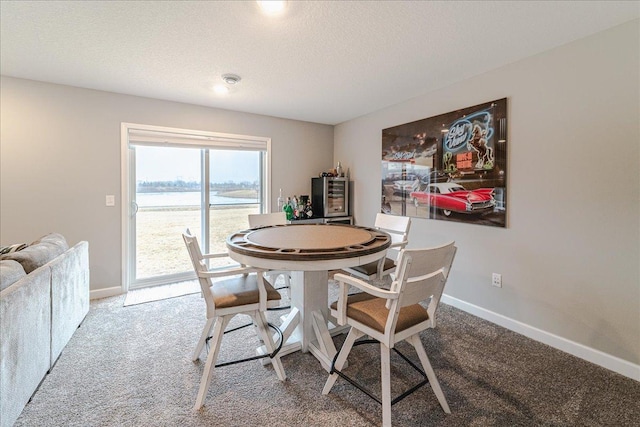 dining space with carpet, baseboards, and a textured ceiling