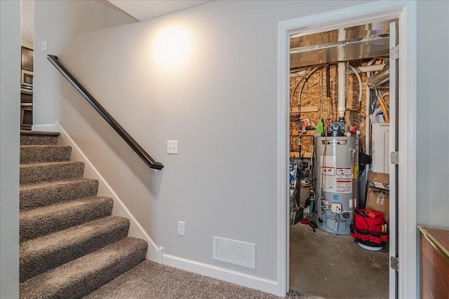 staircase featuring visible vents and gas water heater