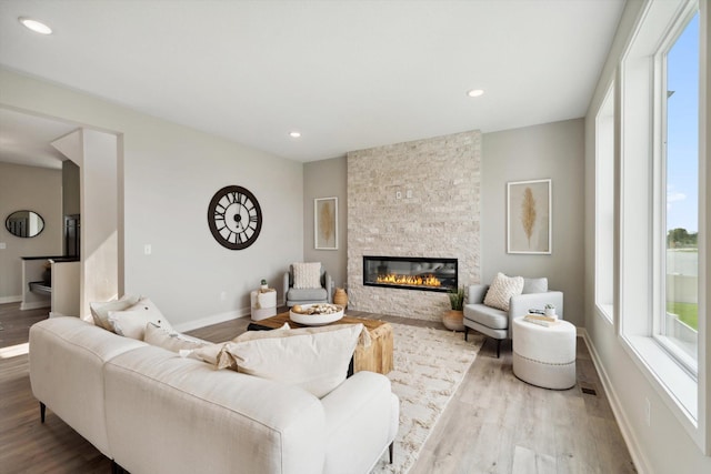 living area with a large fireplace, baseboards, and wood finished floors