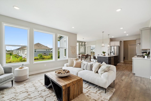 living area with a notable chandelier, light wood-type flooring, baseboards, and recessed lighting