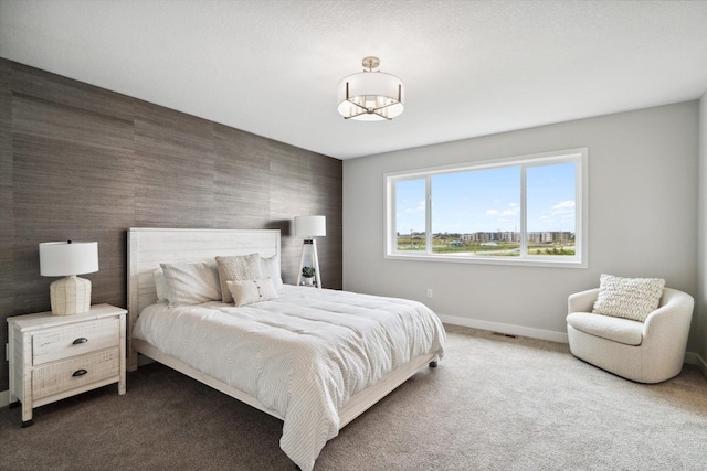 bedroom with an accent wall, baseboards, and carpet flooring