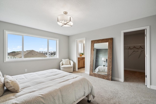 carpeted bedroom featuring a walk in closet, a closet, and baseboards