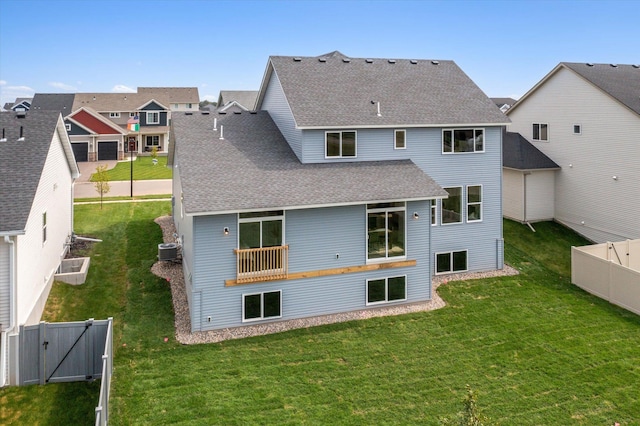 back of property with a shingled roof, a gate, a fenced backyard, and a lawn