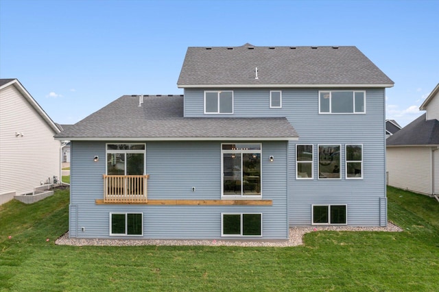 rear view of house with a shingled roof and a lawn