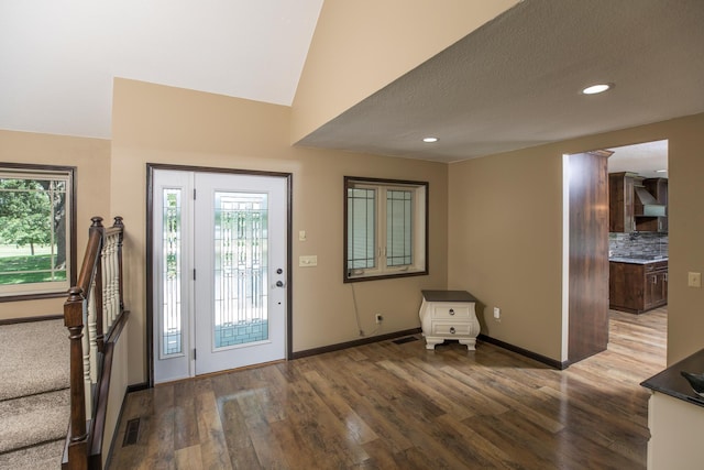 entryway with lofted ceiling, wood finished floors, visible vents, and baseboards